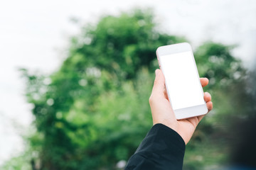 Woman hand hold using smart phone in nature outdoor park green bokeh light abstract background.