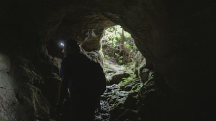 Man exploring cave with lantern on head