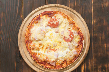 Ready-made pizza on wooden background.
