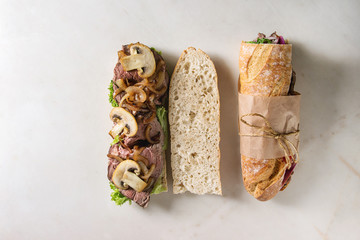 Opened and tied beef baguette sandwich with champignon mushrooms, green salad, fried onion over...