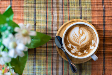 Latte art coffee cup on colors background with flowers pot