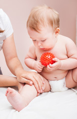 Little baby receiving osteopathic treatment of her leg in pediatric clinic
