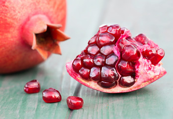 Pomegranate red sweet fruits with seeds on wooden background