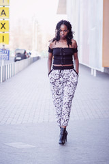 Young woman dressed in casual clothes walking on the street, soft focus background
