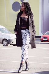 Young woman dressed in casual clothes walking on the street, soft focus background