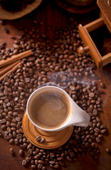 cup of coffee and coffee beans in a sack on dark background, top view