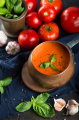 Traditional Italian tomato soup gazpacho with basil. Dark background.