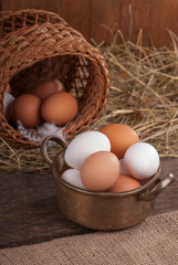 Brown eggs in wooden basket. Broken egg with yolk in background