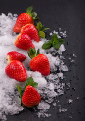 Strawberries, mint and iceon the black background