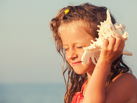 Child put the shell to her ear