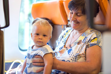 Fototapeta premium Grandmother and baby boy, traveling on a train, going on a jorney together, older sibling sitting next to them