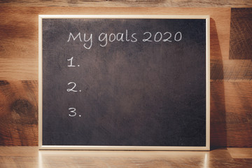New Year resolution 2020, Chalkboard with golden frame in front of wooden background