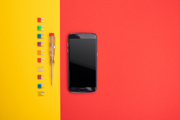 Set of electrical tool with black smartphone on colorful background