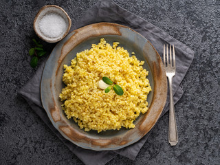 Bulgur wheat. Boiled bulghur cereal in plate on dark grey stone table. Healthy vegetarian food, top view