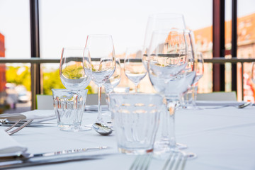Empty glasses on a table covered with a white tablecloth in front of the panoramic window