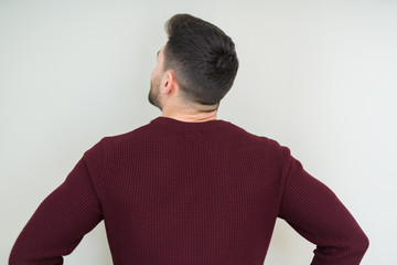 Young handsome man wearing a sweater over isolated background standing backwards looking away with arms on body
