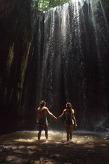 couple in love under a waterfall in a cave