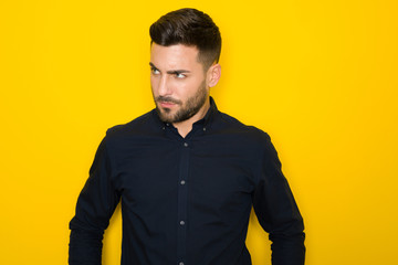 Young handsome man possing and modeling over yellow isolated background