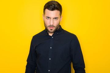 Obraz premium Young handsome man possing and modeling over yellow isolated background