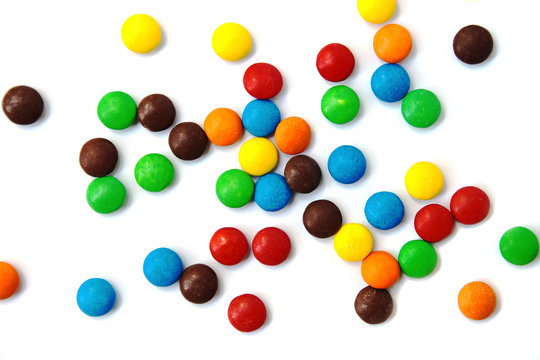  Small multicolored candies scattered on white isolated background
