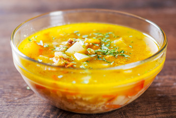 chicken soup with vegetables and rice in glass Bowl on wooden table background