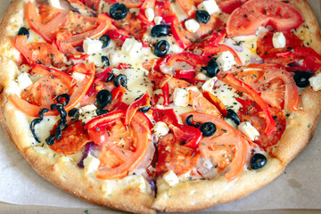 Fragrant delicious Greek pizza in a cardboard box on a light background. The view from the top. Order for a group of friends.