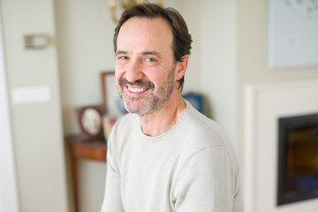 Handsome middle age man smiling looking at the camera at home