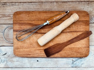 Items for cooking, rolling pin, whisk, spatula on a wooden Board. Things are on the floor
