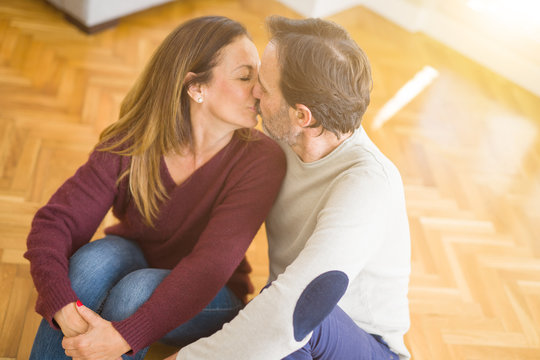 Beautiful romantic couple sitting together on the floor kissing in love at home