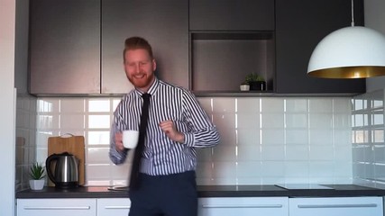 Young Ginger Businessman doing a victory dance in the kitchen