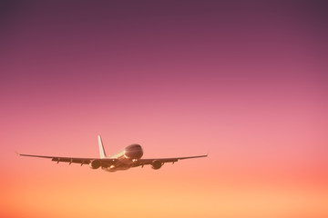 Fototapeta premium Airplane flying on sunset sky abstract background. Copy space of business summer vacation and travel adventure concept.