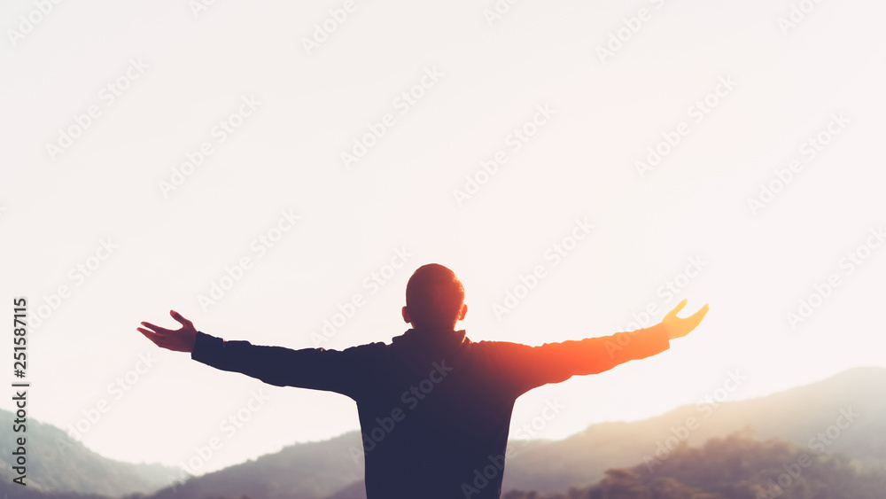 Poster copy space of man rise hand up on top of mountain and sunset sky abstract background.