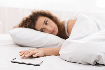 Young woman in bed being woken by mobile phone