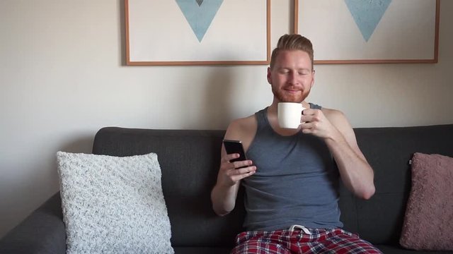 Young Ginger Man checking social media and enjoying a cup of coffee