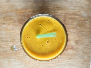 Glass of pumpkin smoothie beverage standings on a wooden surface