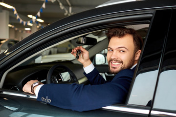 Fototapeta na wymiar Male driver smiling holds the keys to the car
