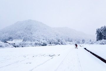 Lone man in the distant photographing the beautiful winter landscape of the snowy mountains and the snow-covered fields in Kyoto Prefecture's Miyama village.