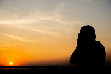 Silhouette Young asian muslim man praying on sunset,Ramadan festival concept