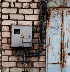 old electric meter in a protective box fortified on a brick wall with white brick