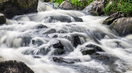 Fototapeta na wymiar Beautiful rapid with fast flowing water and rocks, long exposure. Natural seasonal travel outdoor background in Finland