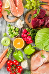Trendy pegan diet - vegan plus paleo diet food concept, many fresh vegetables, fruits, raw beef and chicken meat, salmon fish, white wooden background top view copy space