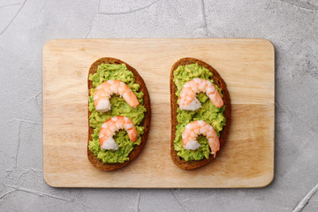 sandwich with guacamole and shrimp on cement background