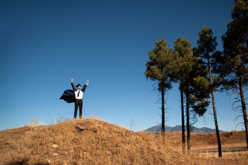 Young man stands atop a mountain and cheers