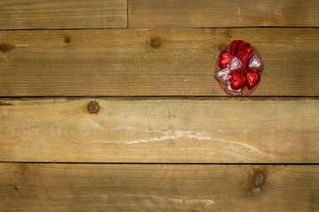 Valentine's Day Background with heart shaped chocolates in a bag on a wooden texture