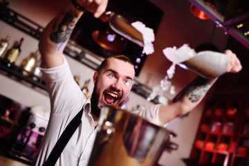 the bartender at a party in a nightclub pours ice for cocktails and screams happily against the bar
