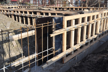 Iron and wooden framework to build a house foundation uder construction. Incomplete house foundation construction site.