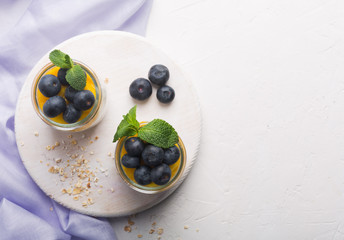 Glass of yogurt with blueberries and mango mousse on a white background