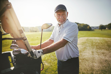 Smiling senior man ready to play a round of golf