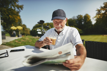 Smiling senior man drinking coffee after a round of golf