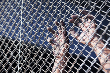 hands of prisoner in jail background.